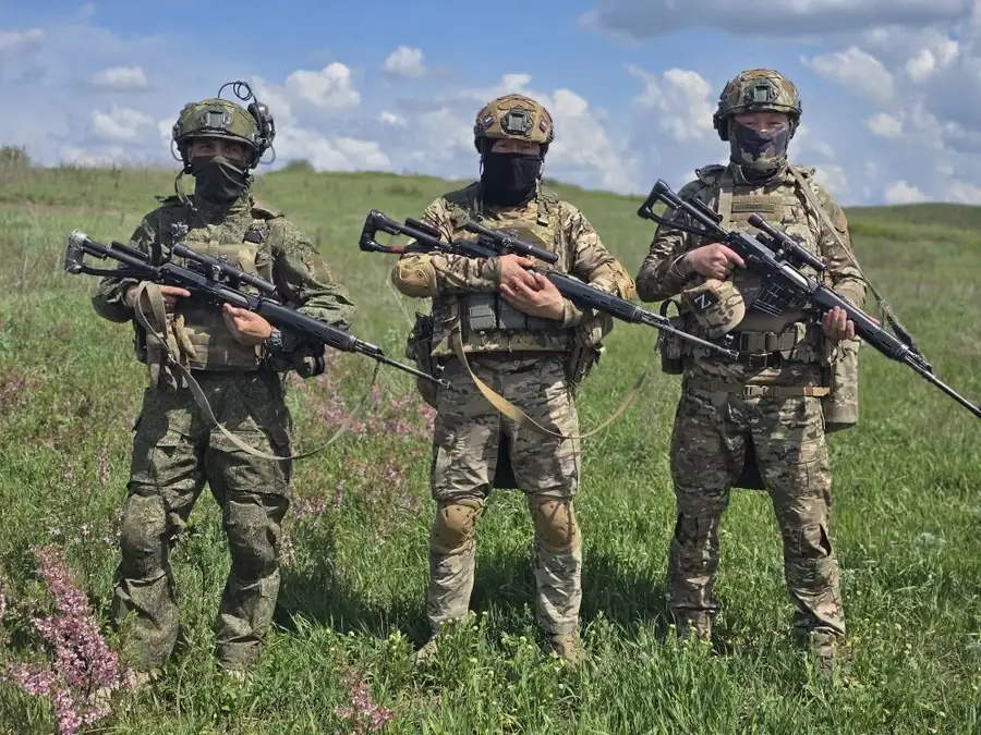 Три бойца в полевой форме с оружием на фоне поля